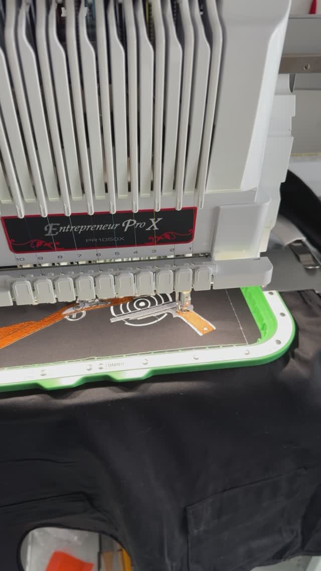 Broderie du motif Saintes Tir Sportif en cours de réalisation sur un gilet noir